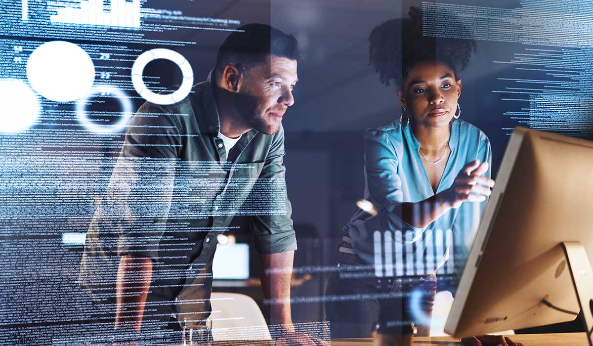 Colleagues looking at a computer with lines of code